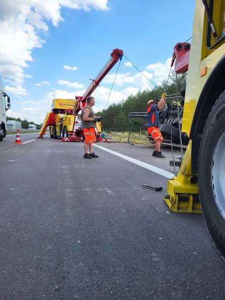 Bergungsteam sichert einen verunglückten Lkw auf der Autobahn, Schwerlastkran hebt das Fahrzeug an, Einsatzkräfte in Warnkleidung arbeiten auf gesperrter Fahrbahn bei Tageslicht.